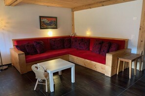 Ein modernes Wohnzimmer mit einem roten Ecksofa, einem weißen Couchtisch und einer hölzernen Bank.