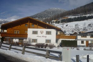 A hotel with a prominent sign reading 'Hans Wolf' and a mountainous backdrop. - Holiday apartment with 2 bedrooms (Nauders)