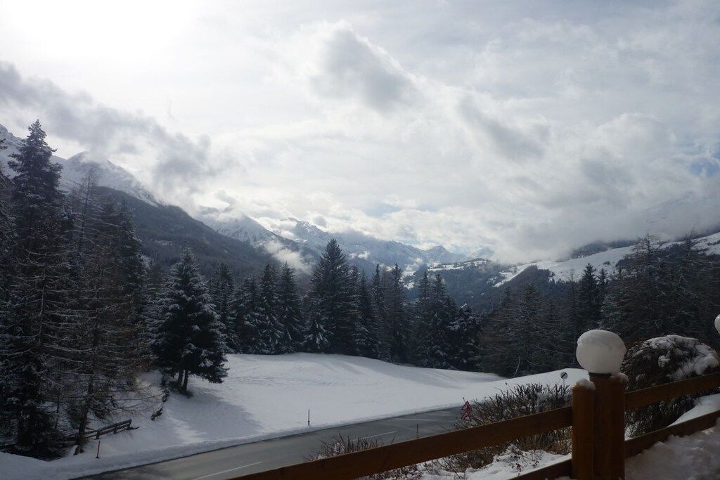 A snow-covered landscape with a wooden fence and a road.