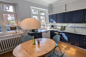 Eine moderne Küche mit dunklen Schränken, einem runden Holztisch und einem großen Fenster.