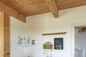 Ein Zimmer mit Holzboden, weißen Wänden, einem Regal mit Dekoration, einer Kreidetafel mit Schrift und einer Holzkiste.