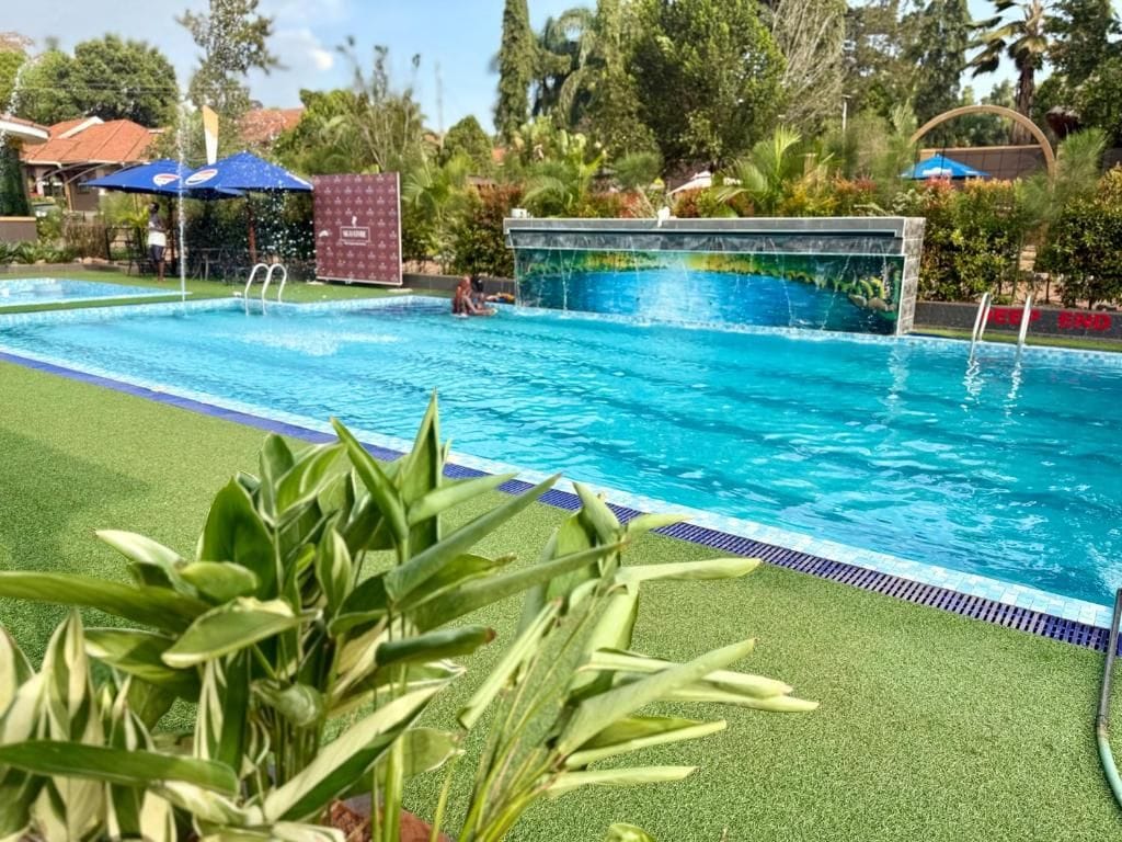 A swimming pool with a clear blue water feature, surrounded by artificial grass and palm trees.
