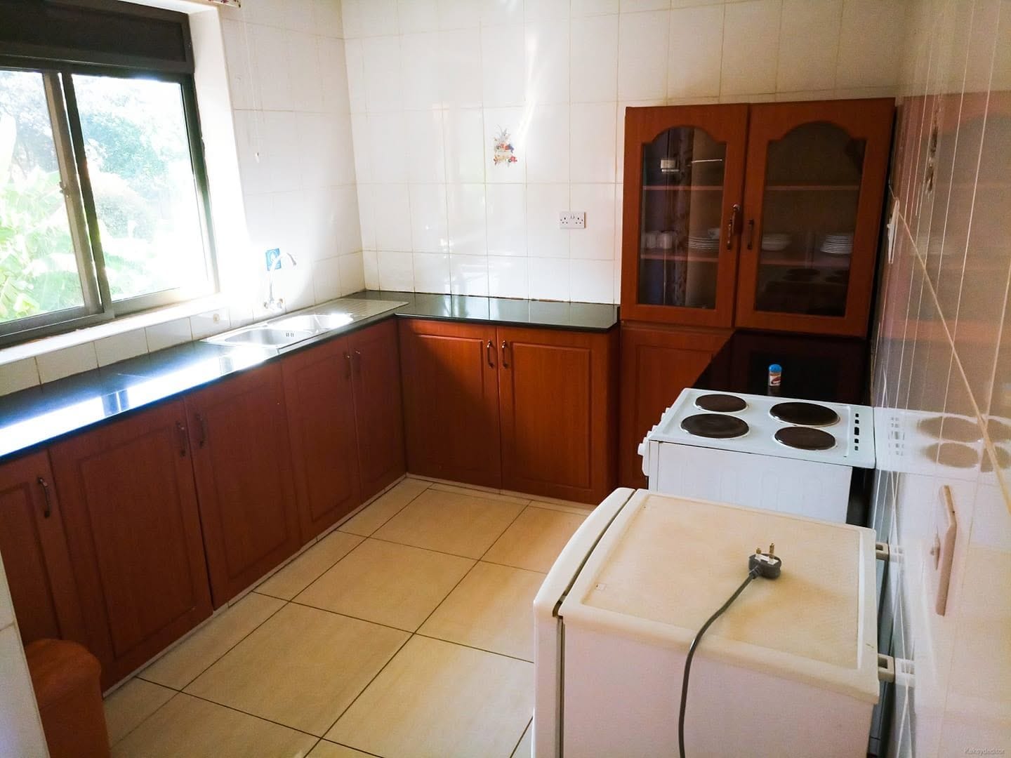 A kitchen with wooden cabinets, a white stove, and a window.