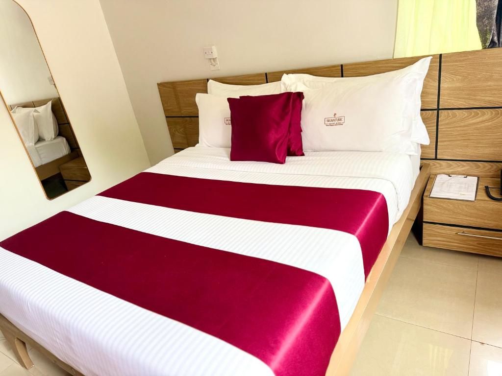 Habitación de hotel con cama, cabecera de madera, mesita de noche y espejo.