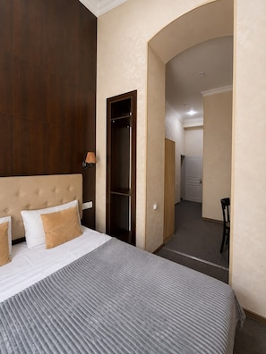 A hotel room with a large bed, a wardrobe, a desk, and an arched doorway leading to another room. - La Casa Nizami Street (Baku)