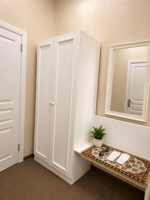 Un baño con un armario blanco, una planta pequeña, un espejo y un suelo estampado.