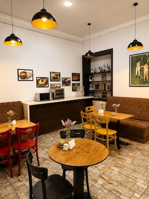 A restaurant interior with round tables, red and black chairs, a bar area, and wall-mounted artwork. - La Casa Nizami Street (Baku)