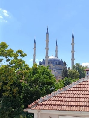 A mosque with a large dome and four minarets, surrounded by trees and buildings.