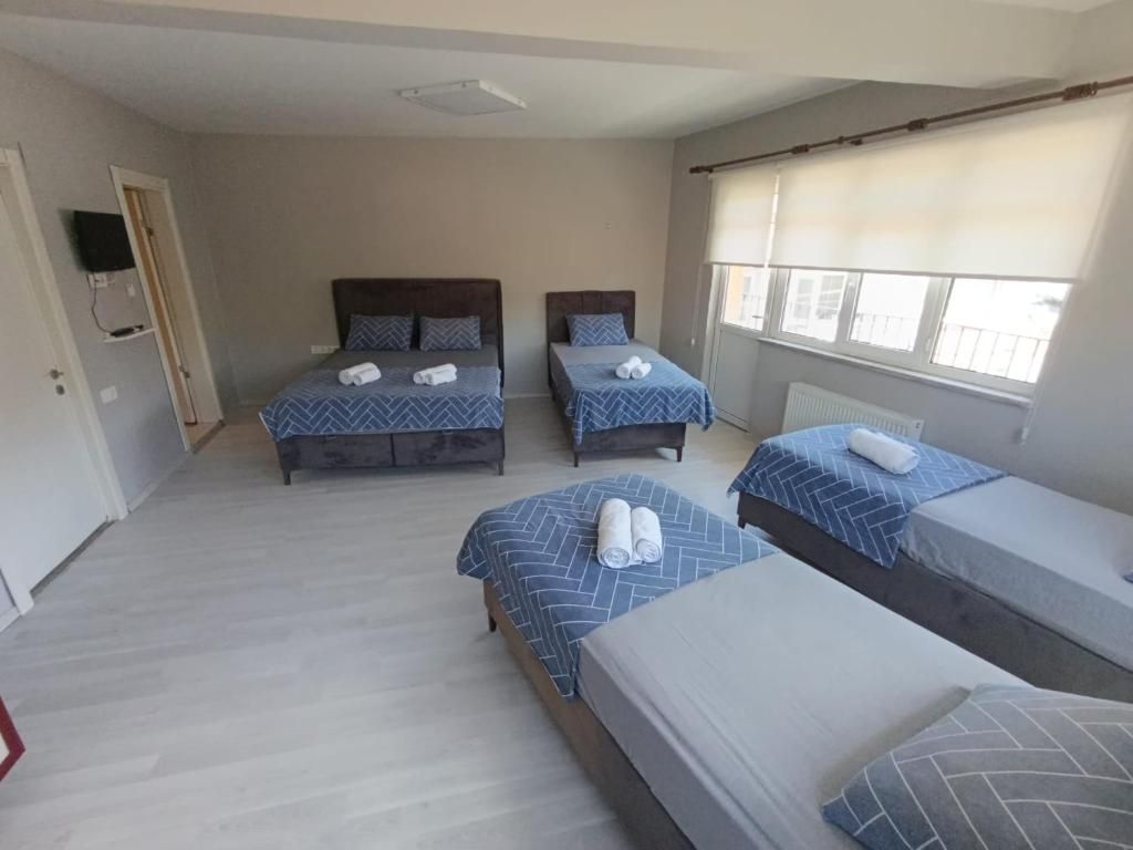 Ein Hotelzimmer mit drei Betten, einem Fernseher und einem Fenster mit Jalousien.