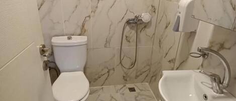 A bathroom with a toilet, shower, and sink.