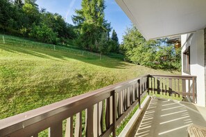 Eine Holzterrasse mit Blick auf einen Rasen und Bäume.