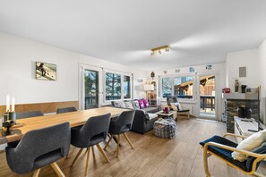 Ein modernes Interieur mit einem Holzesstisch, grauen Polsterstühlen, einer Couch und einem Kamin.