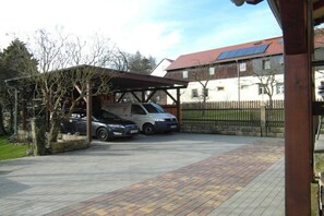 A covered parking area with two cars parked under a wooden structure. - Holiday apartment with 1 bedroom (Rathewalde)