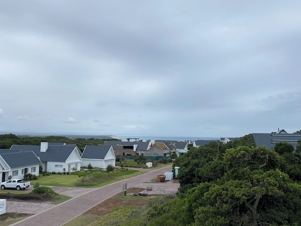 A residential area with houses, a driveway, and a view of the sea.