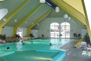 An indoor swimming pool with yellow sun loungers and potted plants. - Holiday apartment with 1 bedroom (Koserow)