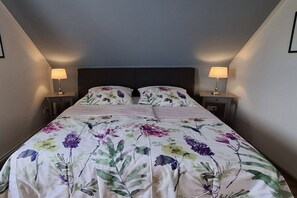 Ein Schlafzimmer mit einem Bett, zwei Nachttischen und Lampen.