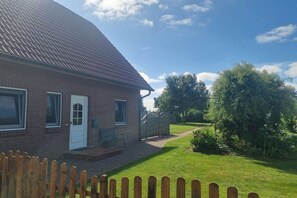 A brick house with a sloped roof, a front door, and a small porch. - Holiday home with 3 bedrooms (Drochtersen)