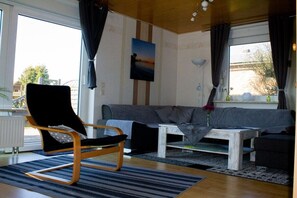 A living room with a sofa, a chair, a coffee table, and a painting on the wall. - Holiday home with 3 bedrooms (Drochtersen)