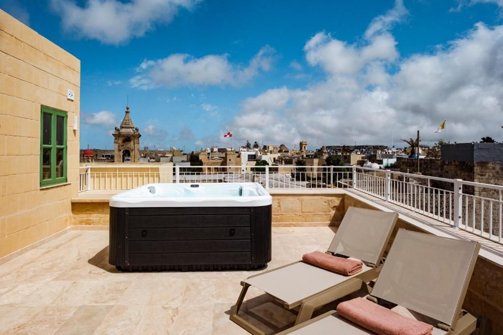 Una terraza en la azotea con jacuzzi, sillas de descanso y vistas panorámicas de la ciudad.