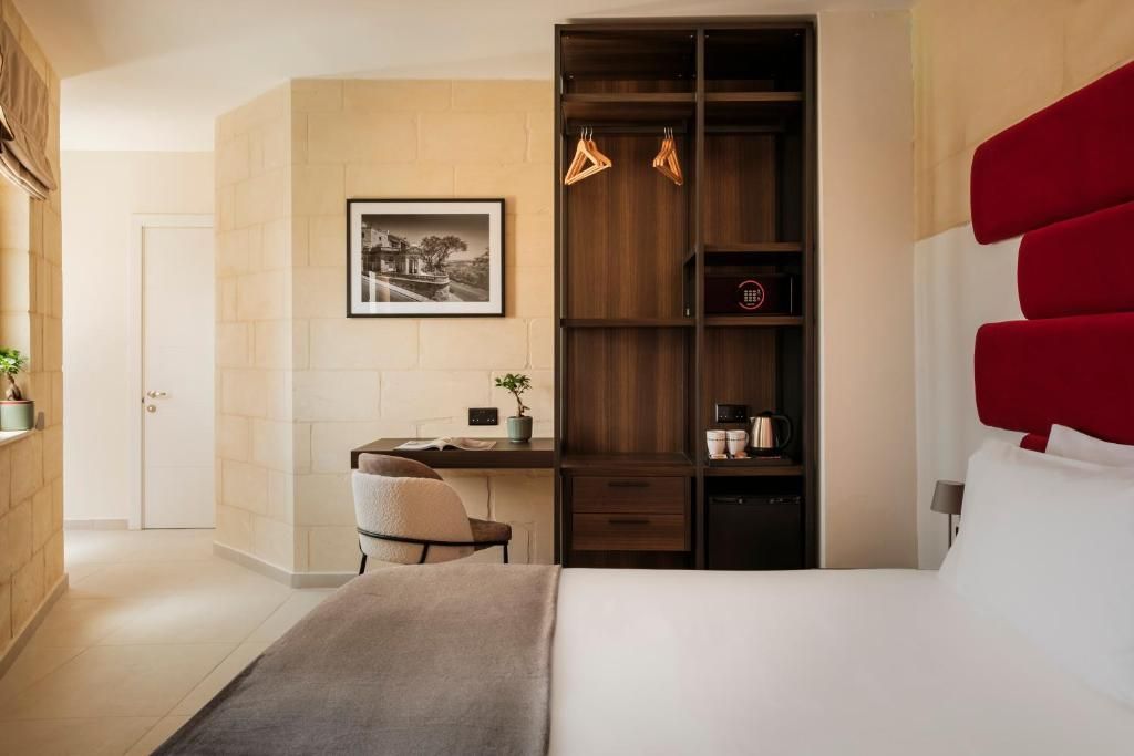 Una habitación de hotel con una cama, un escritorio y un armario.