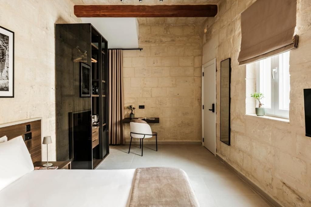 A bedroom with a bed, a desk, and a window.