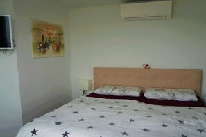 A single bed with a star-patterned bedspread, a headboard, and a wall-mounted air conditioner. - Holiday home with 2 bedrooms (Bitterfeld)