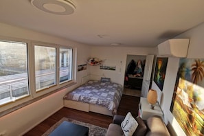 Ein Schlafzimmer mit einem Bett, einem Schreibtisch, einem Stuhl, einem Fenster und einer Tür zu einem anderen Raum.