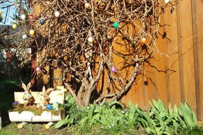 Ein Baum mit bunten Verzierungen und eine kleine Bank mit einer Hasenfigur.