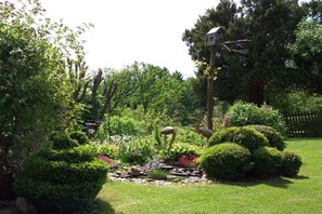 A garden with various plants, a birdhouse, and a small pond. - Holiday apartment with 1 bedroom (Porschdorf)
