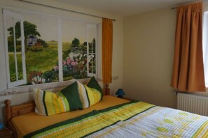 A bedroom with a bed, a window with a view of a landscape, and a curtain. - Holiday apartment with 1 bedroom (Porschdorf)
