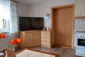 A kitchen with a built-in oven, a television on a cabinet, and a door leading to another room. - Holiday apartment with 1 bedroom (Porschdorf)