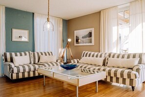 A living room with striped sofas, a glass coffee table, and a sailboat model. - Holiday apartment with 3 bedrooms (Zinnowitz)
