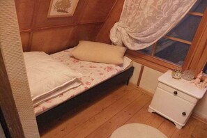 A small bedroom with a single bed, a nightstand with a clock, and a window with curtains. - Finnish-style cabin in a quiet location by the lake (Garden)