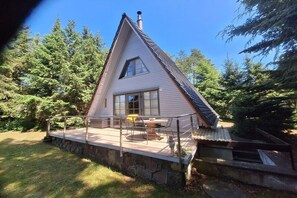 A house with a sloped roof, a stone foundation, and a covered patio with outdoor furniture. - Finnish-style cabin in a quiet location by the lake (Garden)