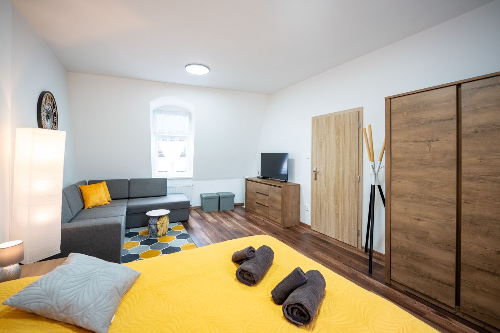 Ein modernes Schlafzimmer mit einem Bett, einer Couch, einem Fernseher und einem Kleiderschrank.