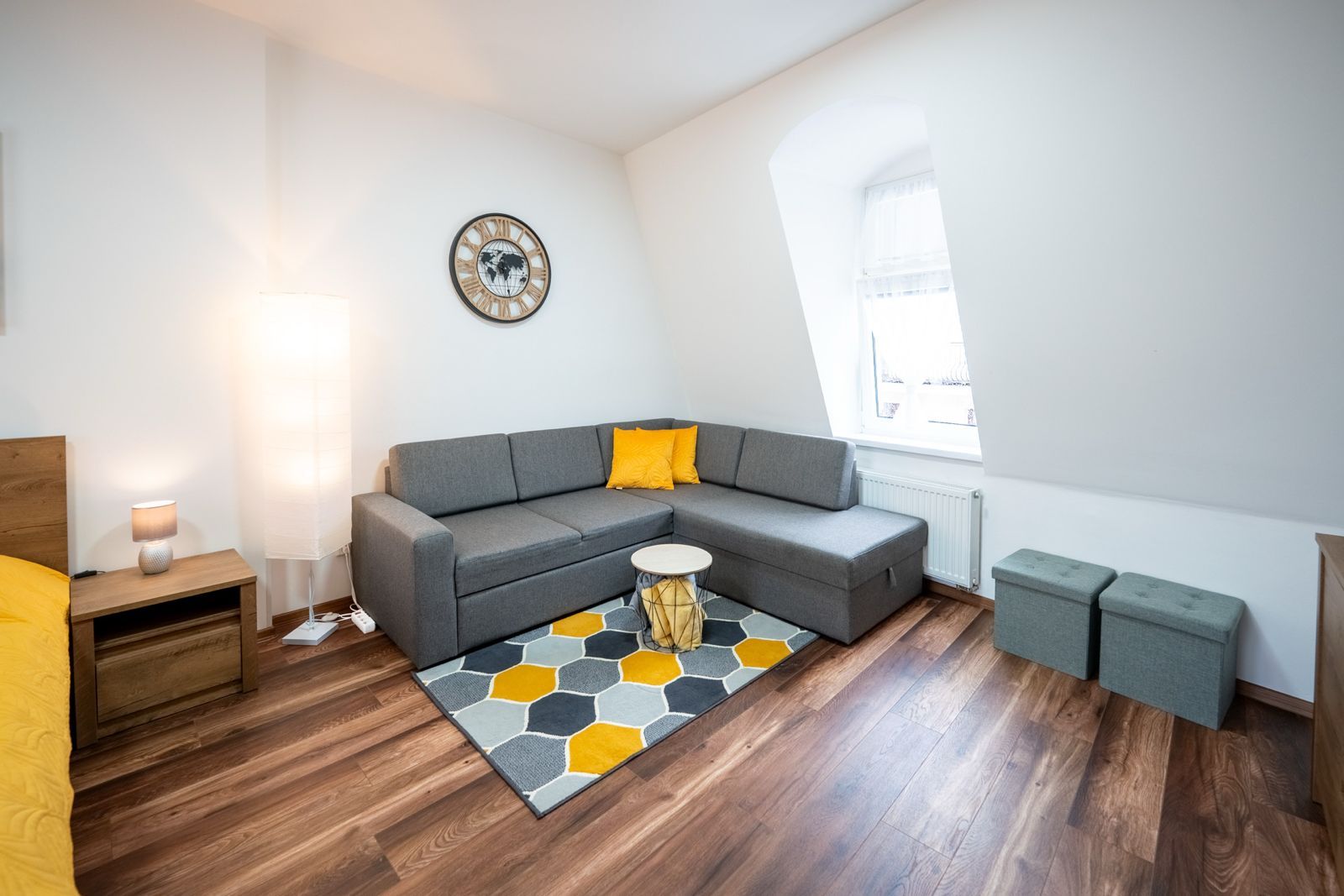 Un salon moderne avec un canapé gris, une table basse ronde et un tapis à motifs hexagonaux.
