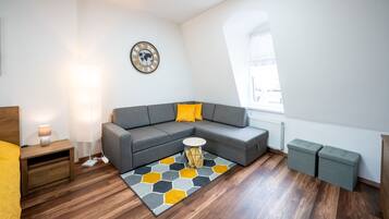 Un salon moderne avec un canapé gris, une table basse ronde et un tapis à motifs hexagonaux.