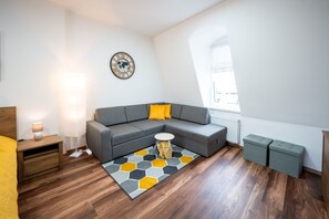 Un salon moderne avec un canapé gris, une table basse ronde et un tapis à motifs hexagonaux.