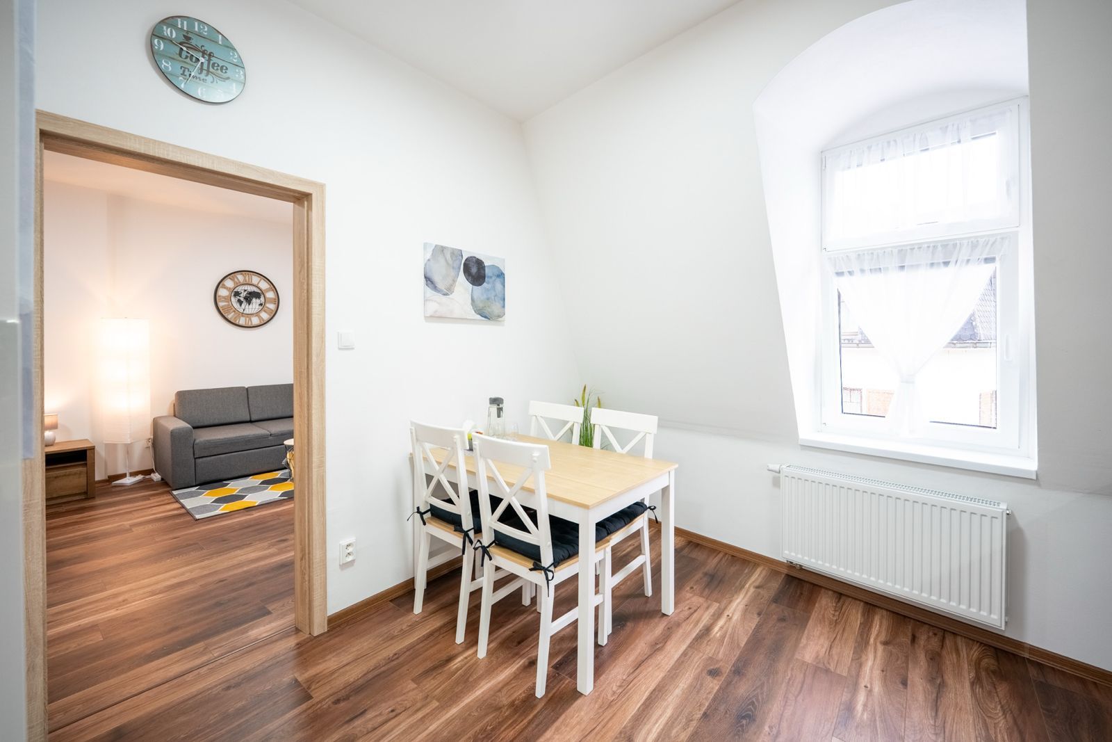 Une pièce comprenant une table à manger, des chaises, un canapé, une horloge et une fenêtre.
