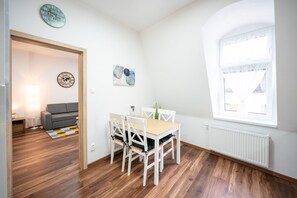 Une pièce comprenant une table à manger, des chaises, un canapé, une horloge et une fenêtre.