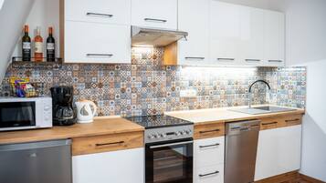 Eine moderne Küche mit weißen Schränken, einer gemusterten Spritzschutzwand und Edelstahlgeräten.