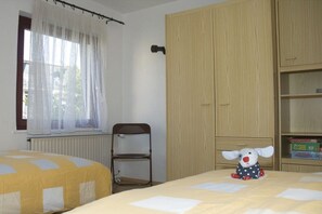 Une chambre à coucher avec un lit, une chaise, une armoire et un jouet en peluche.