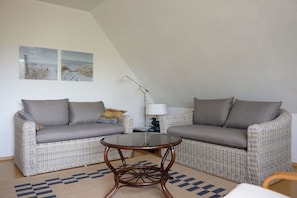 Ein möbliertes Wohnzimmer mit zwei Sofas, einem runden Couchtisch und einer Lampe.