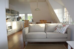 A cozy loft-style living space with a sofa, dining table, and kitchen area. - Holiday apartment in Nieby with swimming pool (Nieby)