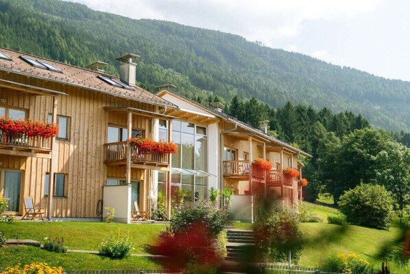 Un chalet en bois doté de balcons, de grandes fenêtres et surplombant un paysage montagneux.