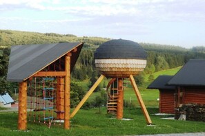 Eine hölzerne Spielkonstruktion mit Kletterwand und einem kugelförmigen Aussichtsturm.