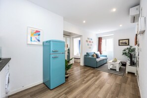 A modern living room with a blue refrigerator, a sofa, and a coffee table. - Modern Apartment in Madrid Near the Royal Palace (Madrid)