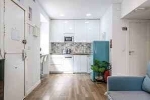 A compact kitchen with white cabinets, a microwave, and a teal refrigerator. - Modern Apartment in Madrid Near the Royal Palace (Madrid)