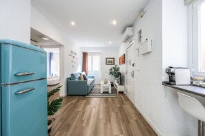 Een moderne keuken met een inbouwoven, een koffieapparaat en een zithoek met een bank en een kleine tafel.