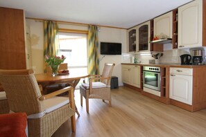 A compact kitchen with a dining area, wooden furniture, and a flat-screen TV. - Bungalow with 2 bedrooms (Reinhardtsdorf-Schöna)